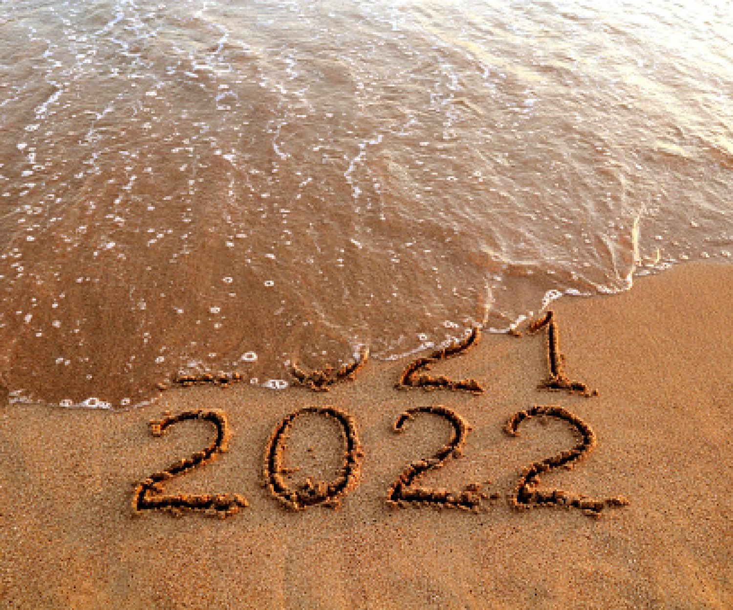 New year 2022 and old year 2021 on sandy beach with waves